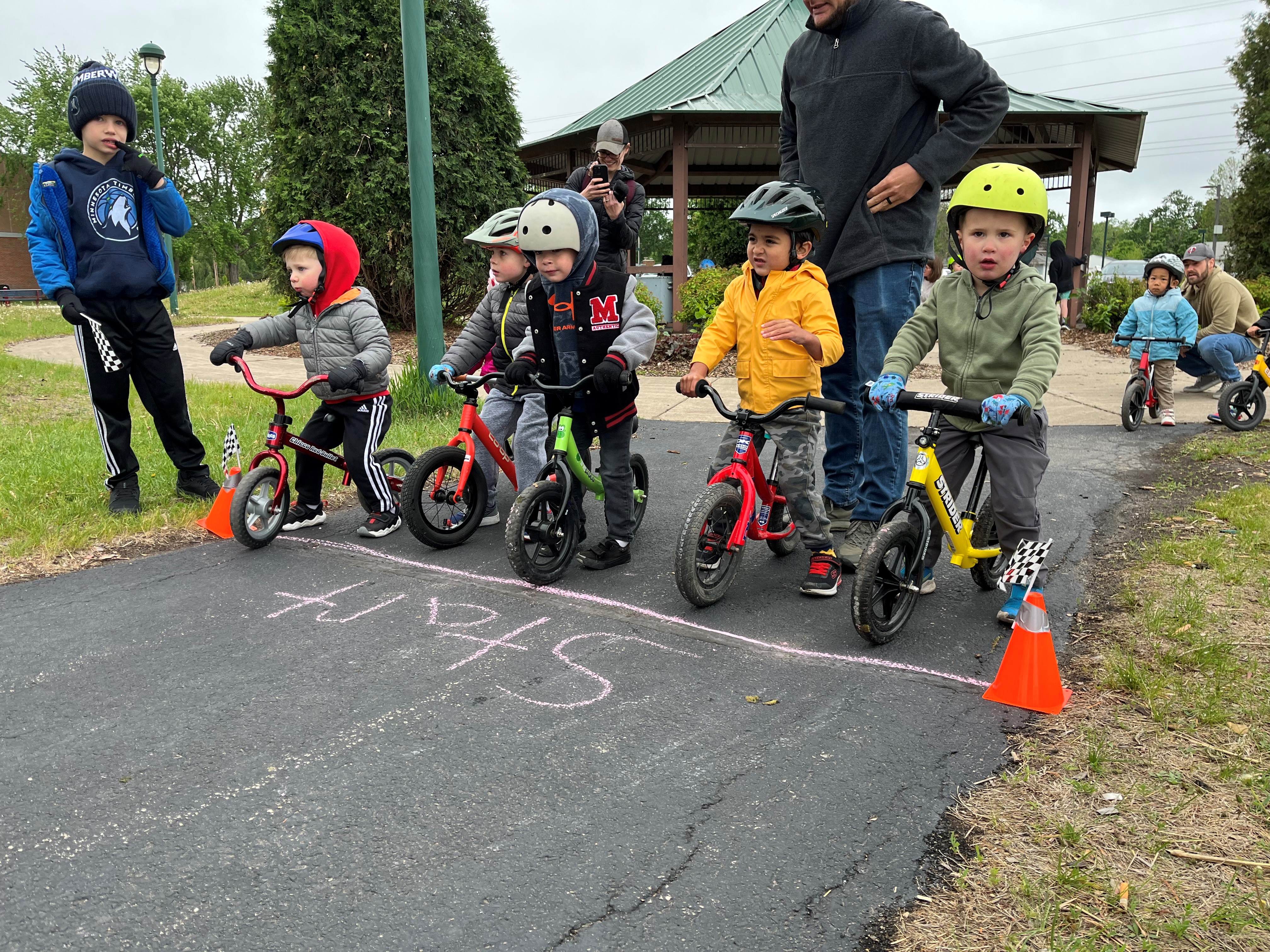 Kids line up at the starting line for a balance bike race.
